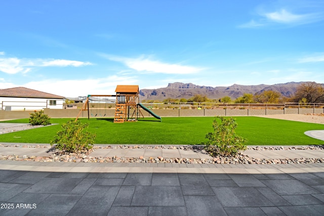 view of yard featuring playground community, fence, and a mountain view