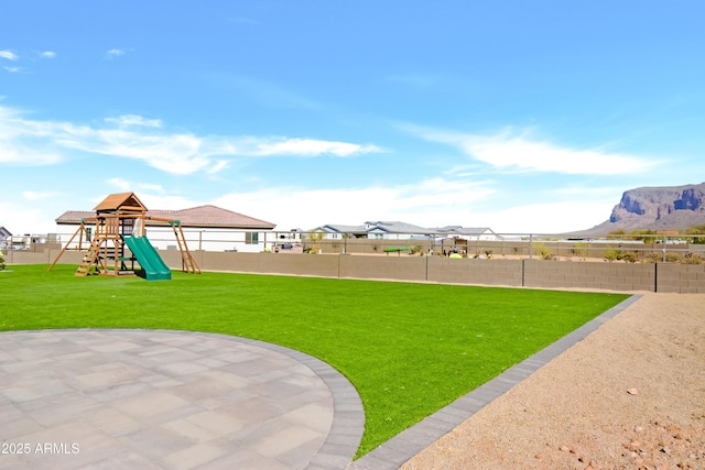 view of yard with a playground, fence, and a mountain view