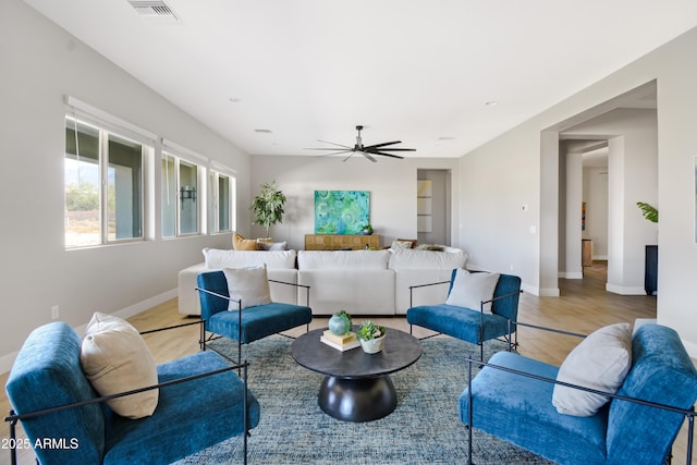 living area featuring a ceiling fan, visible vents, light wood-style flooring, and baseboards