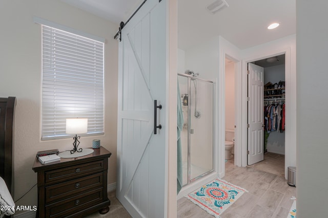 bathroom featuring a shower with shower door and toilet