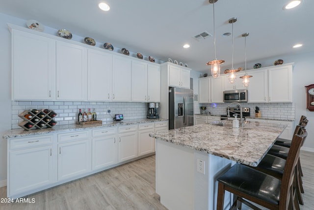 kitchen featuring pendant lighting, sink, an island with sink, white cabinetry, and stainless steel appliances