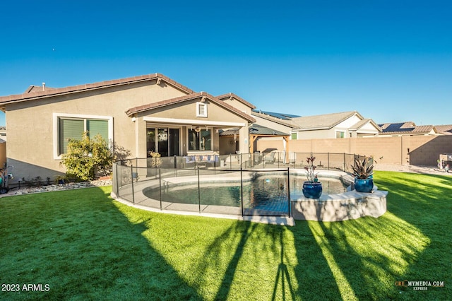 rear view of property featuring a fenced in pool, a patio area, and a yard