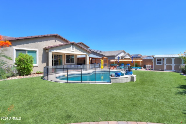 view of swimming pool featuring a lawn, a patio area, and a shed