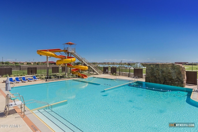 pool featuring a water slide, fence, and a patio