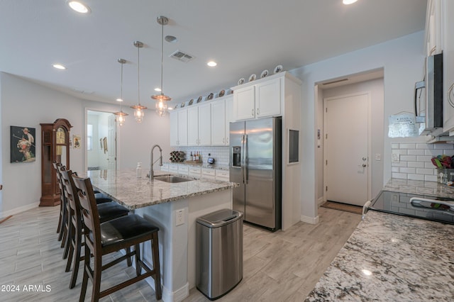 kitchen with sink, stainless steel fridge, decorative light fixtures, decorative backsplash, and white cabinets