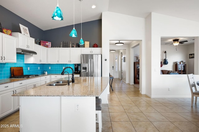 kitchen with light tile patterned flooring, appliances with stainless steel finishes, under cabinet range hood, white cabinetry, and a sink