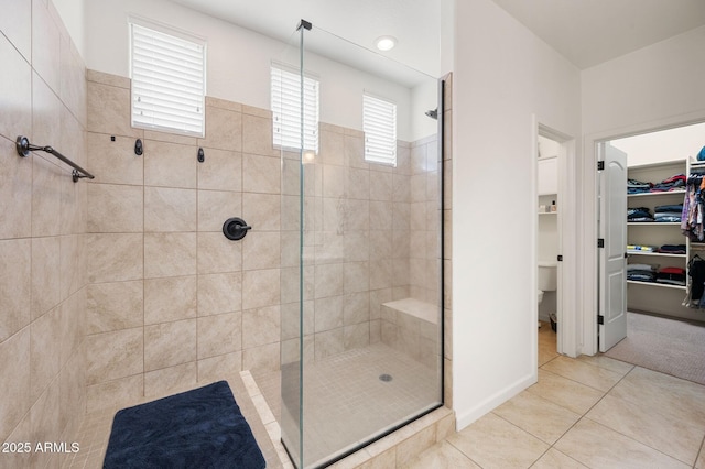 full bathroom with a walk in closet, toilet, a stall shower, and tile patterned flooring
