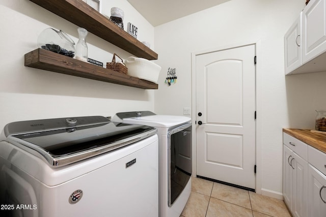 laundry area with cabinet space, independent washer and dryer, and light tile patterned floors