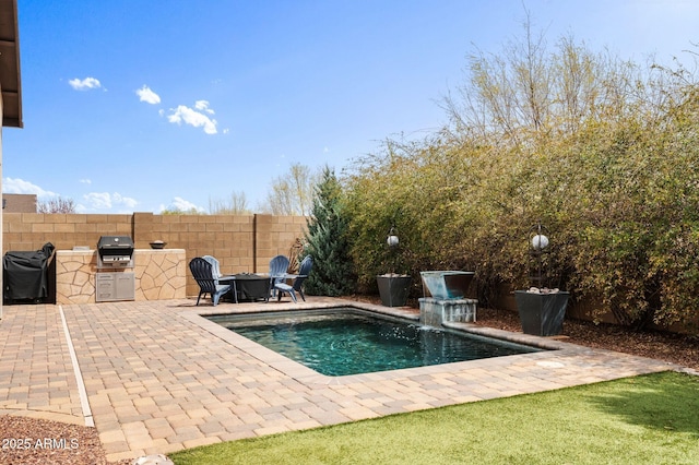view of pool with fence, grilling area, exterior kitchen, and a patio