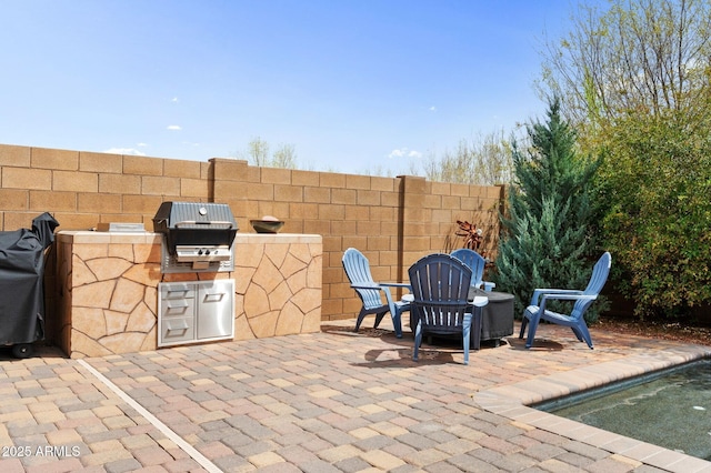 view of patio with a grill, fence, and exterior kitchen