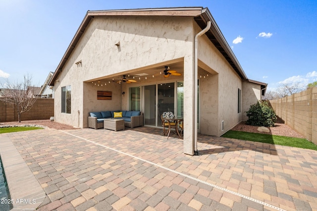 rear view of house with an outdoor living space, a patio area, a ceiling fan, stucco siding, and a fenced backyard