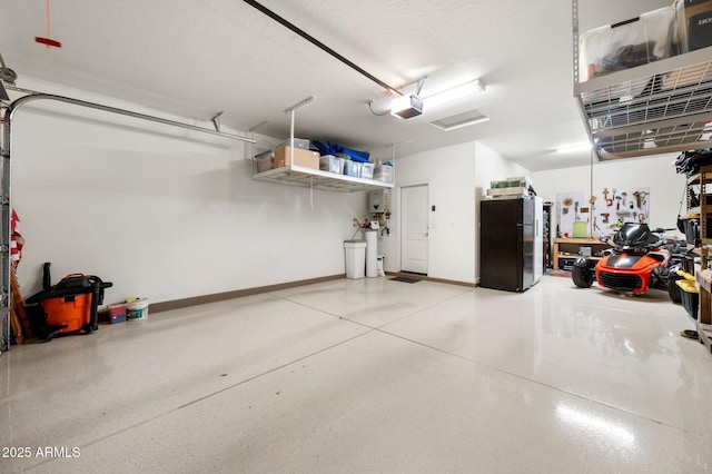 garage featuring a garage door opener, baseboards, and freestanding refrigerator
