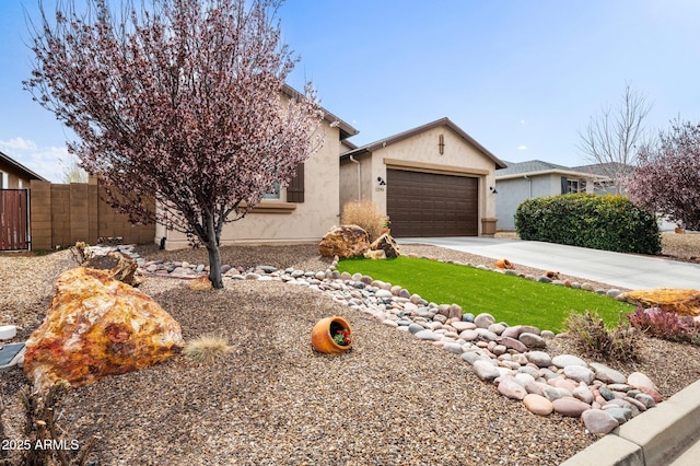 view of front of home with stucco siding, an attached garage, fence, and concrete driveway