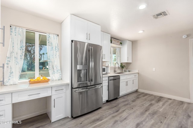 kitchen with white cabinets, light wood-type flooring, stainless steel appliances, and plenty of natural light