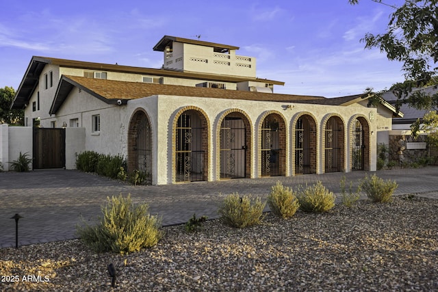 view of front of home featuring stucco siding, a gate, and fence