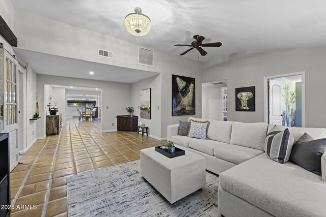 tiled living room with ceiling fan, vaulted ceiling, and baseboards