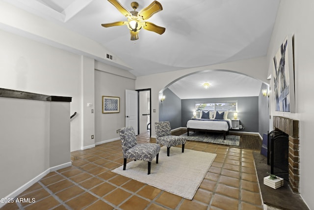 tiled bedroom with arched walkways, vaulted ceiling, a ceiling fan, baseboards, and a brick fireplace