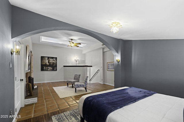 bedroom featuring arched walkways, a fireplace, and baseboards