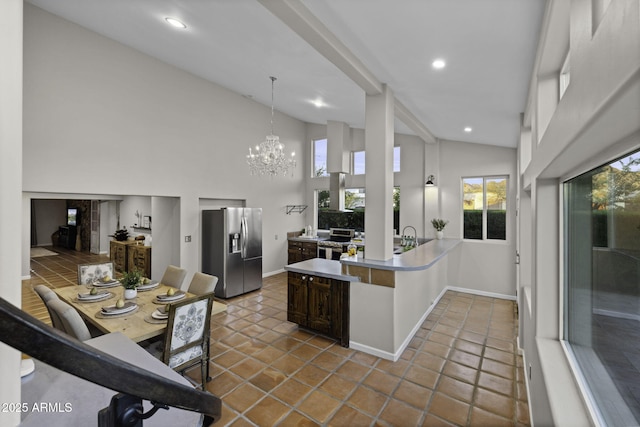 kitchen with stainless steel appliances, a peninsula, light countertops, high vaulted ceiling, and baseboards