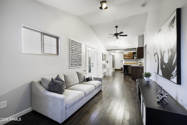living area with ceiling fan, lofted ceiling, dark wood-style flooring, and baseboards