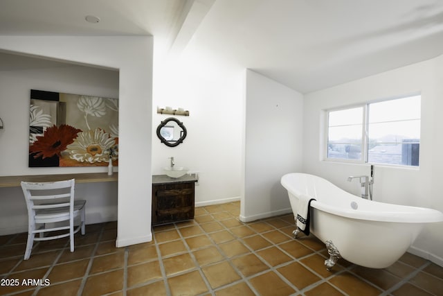 bathroom featuring a freestanding tub, vaulted ceiling, and baseboards