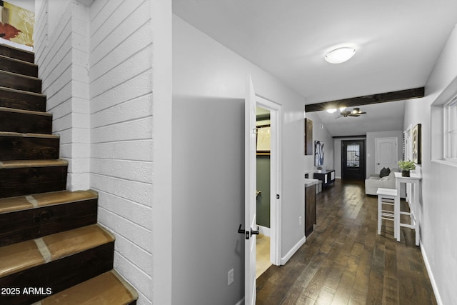 hallway with dark wood-type flooring, baseboards, stairway, and a chandelier