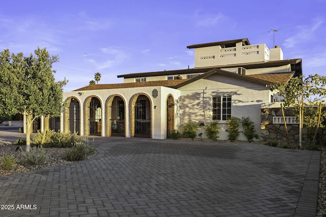 mediterranean / spanish home featuring stucco siding, curved driveway, and a chimney
