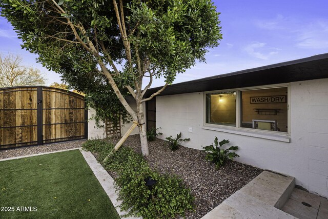 view of home's exterior with concrete block siding and fence