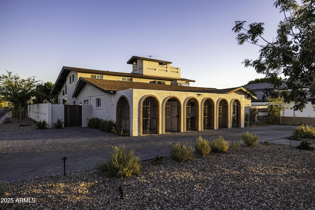mediterranean / spanish-style home with driveway, stucco siding, and fence