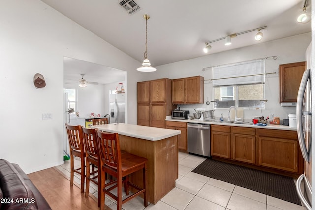 kitchen with ceiling fan, a center island, hanging light fixtures, stainless steel appliances, and a kitchen bar