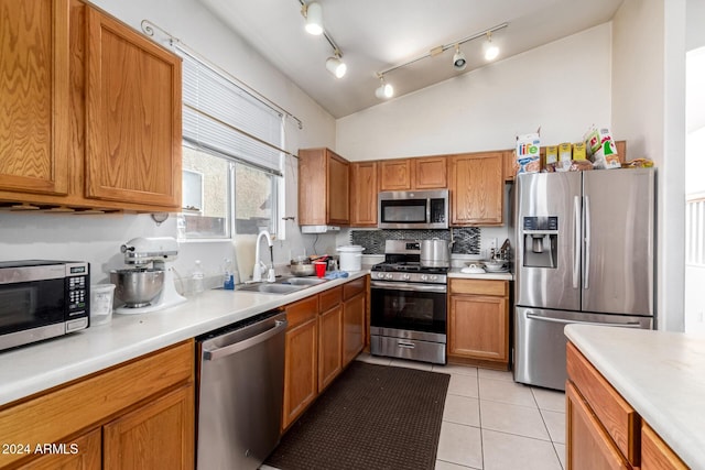 kitchen featuring sink, light tile patterned flooring, lofted ceiling, and appliances with stainless steel finishes