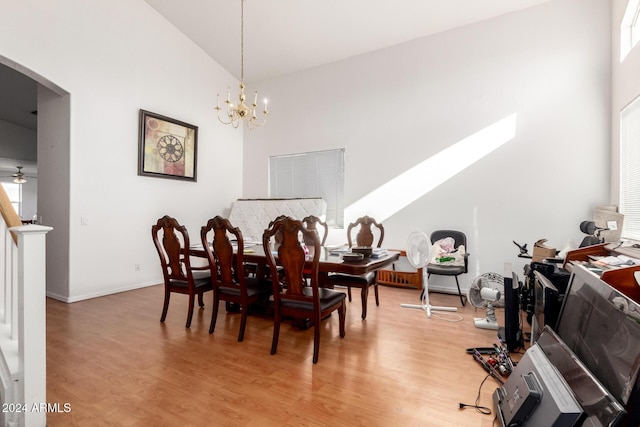 dining room with hardwood / wood-style floors, ceiling fan with notable chandelier, and high vaulted ceiling