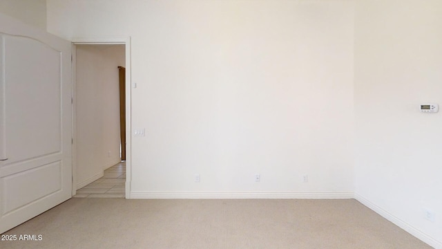 unfurnished room featuring baseboards and light carpet