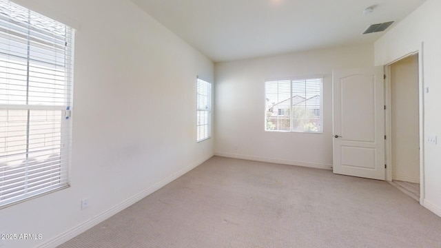 unfurnished room with visible vents, baseboards, and light colored carpet