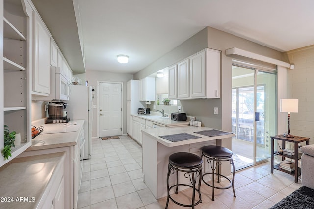 kitchen featuring kitchen peninsula, a breakfast bar, white cabinets, and light tile patterned floors