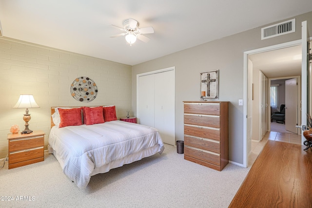 bedroom with ceiling fan, light colored carpet, and a closet