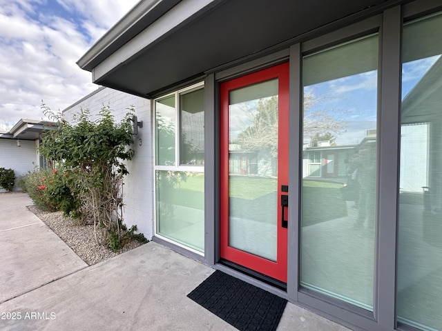 doorway to property featuring brick siding and a patio area