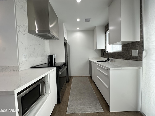 kitchen with recessed lighting, visible vents, appliances with stainless steel finishes, a sink, and wall chimney exhaust hood