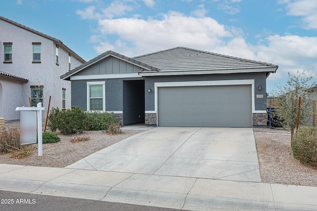 view of front of home with a tile roof, an attached garage, board and batten siding, stone siding, and driveway