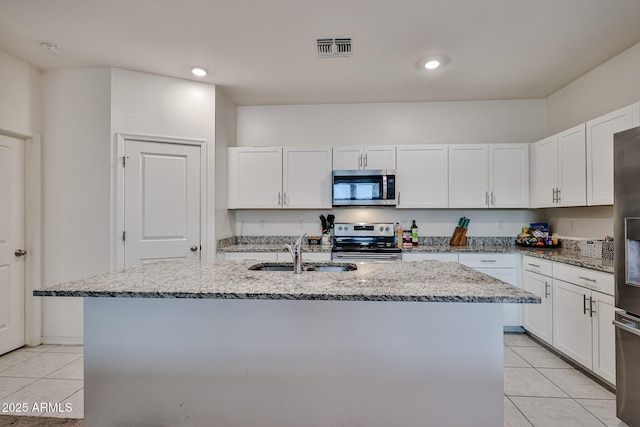 kitchen with visible vents, white cabinets, stainless steel appliances, a sink, and light tile patterned flooring