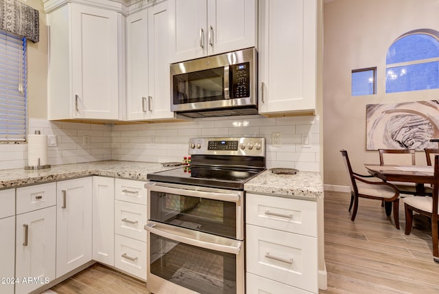 kitchen with appliances with stainless steel finishes, light hardwood / wood-style flooring, and white cabinetry