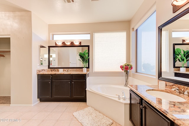 bathroom featuring vanity, a healthy amount of sunlight, tile patterned floors, and a bath