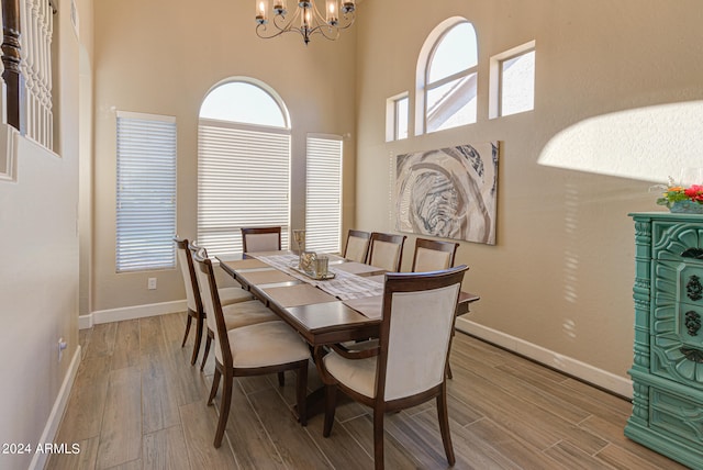 dining space featuring light hardwood / wood-style floors, an inviting chandelier, and a towering ceiling