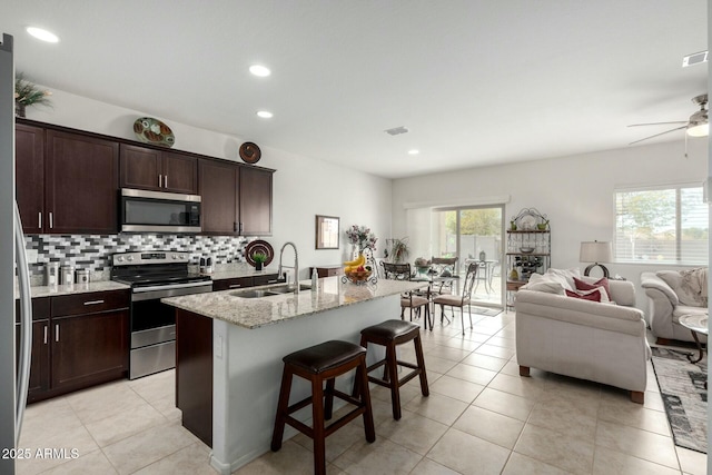 kitchen featuring an island with sink, sink, a breakfast bar area, decorative backsplash, and stainless steel appliances