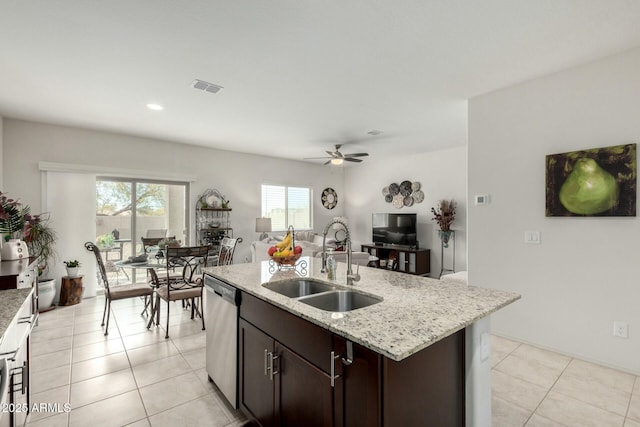 kitchen featuring sink, a center island with sink, dark brown cabinetry, light tile patterned flooring, and stainless steel dishwasher