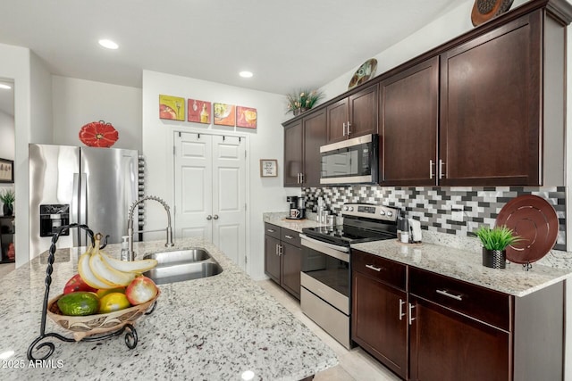 kitchen featuring light stone counters, sink, decorative backsplash, and stainless steel appliances