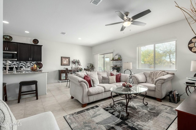 tiled living room with plenty of natural light and ceiling fan