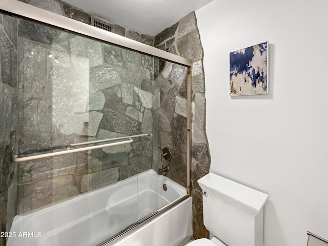 bathroom featuring combined bath / shower with glass door and toilet