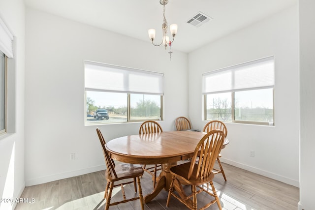 dining area with light hardwood / wood-style flooring, a wealth of natural light, and a chandelier