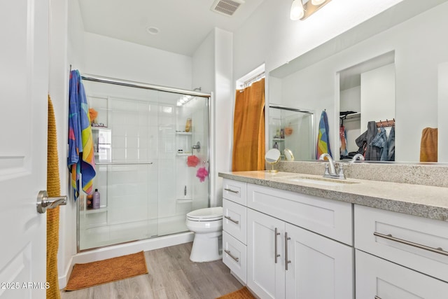 bathroom with vanity, hardwood / wood-style floors, an enclosed shower, and toilet